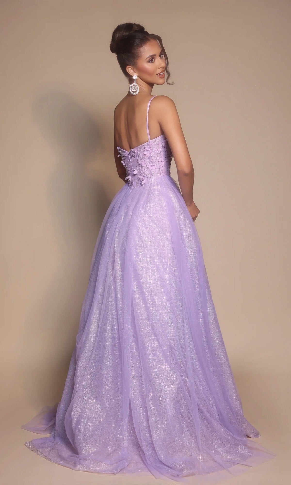 Woman in a glittery Portia and Scarlett PS26146 prom ball gown with a boned-corset bodice, styled with a high bun and dangling earrings.